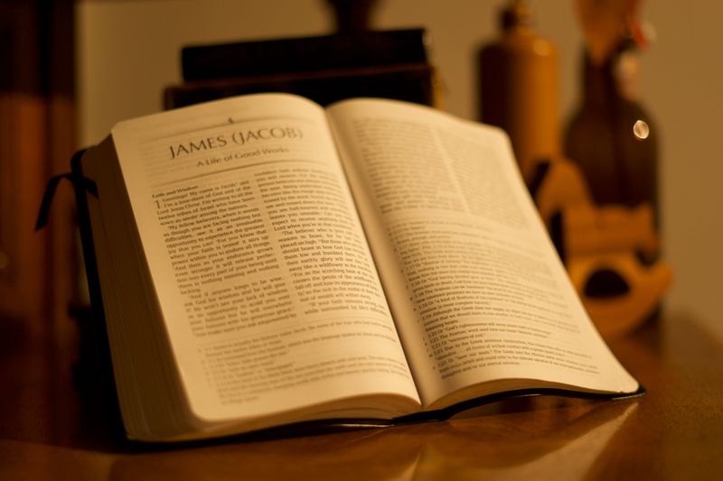 An open Bible on a wooden table in warm light.